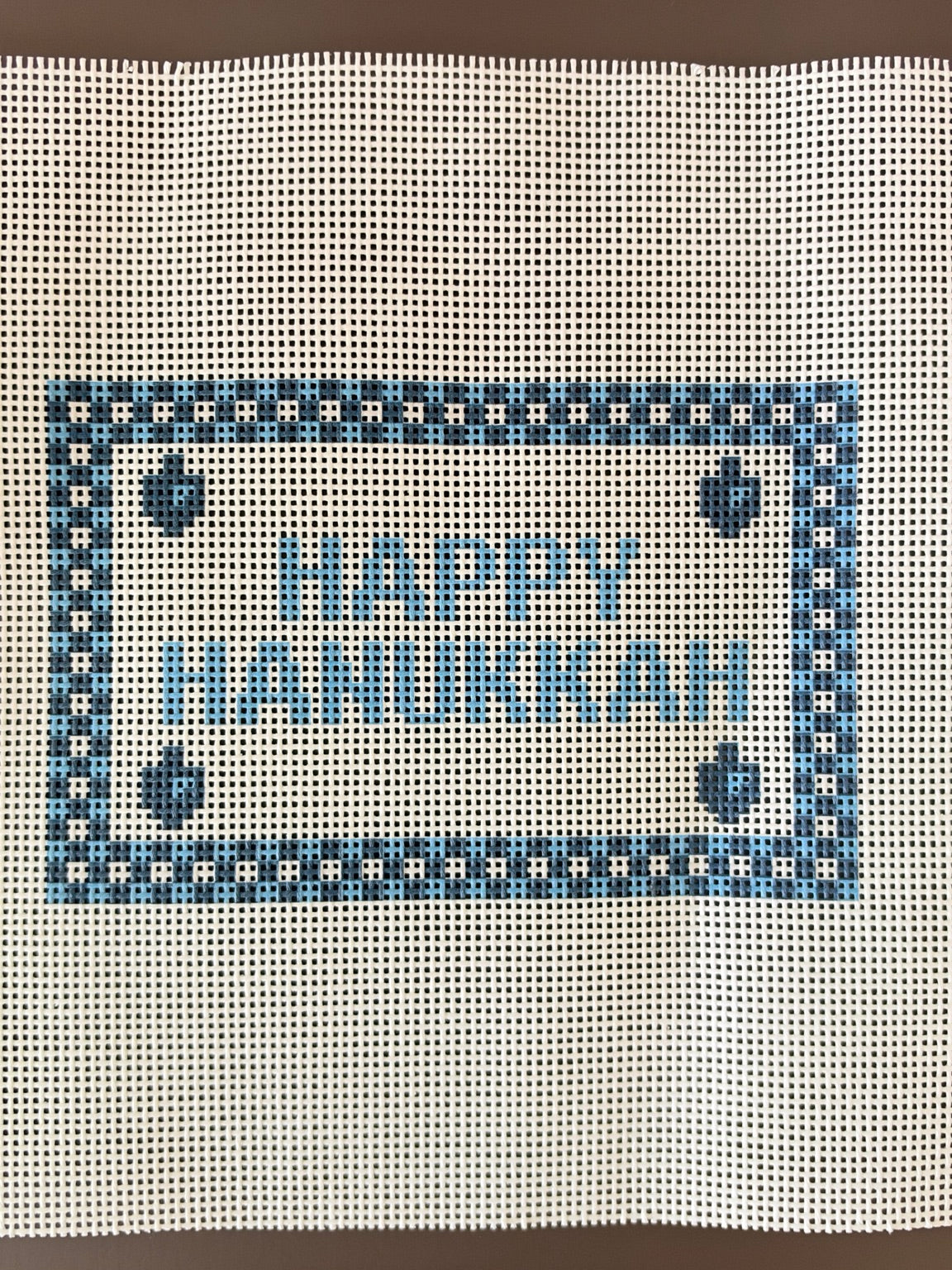 Happy Hanukkah printed needlepoint canvas close-up with blue checked border and dreidels